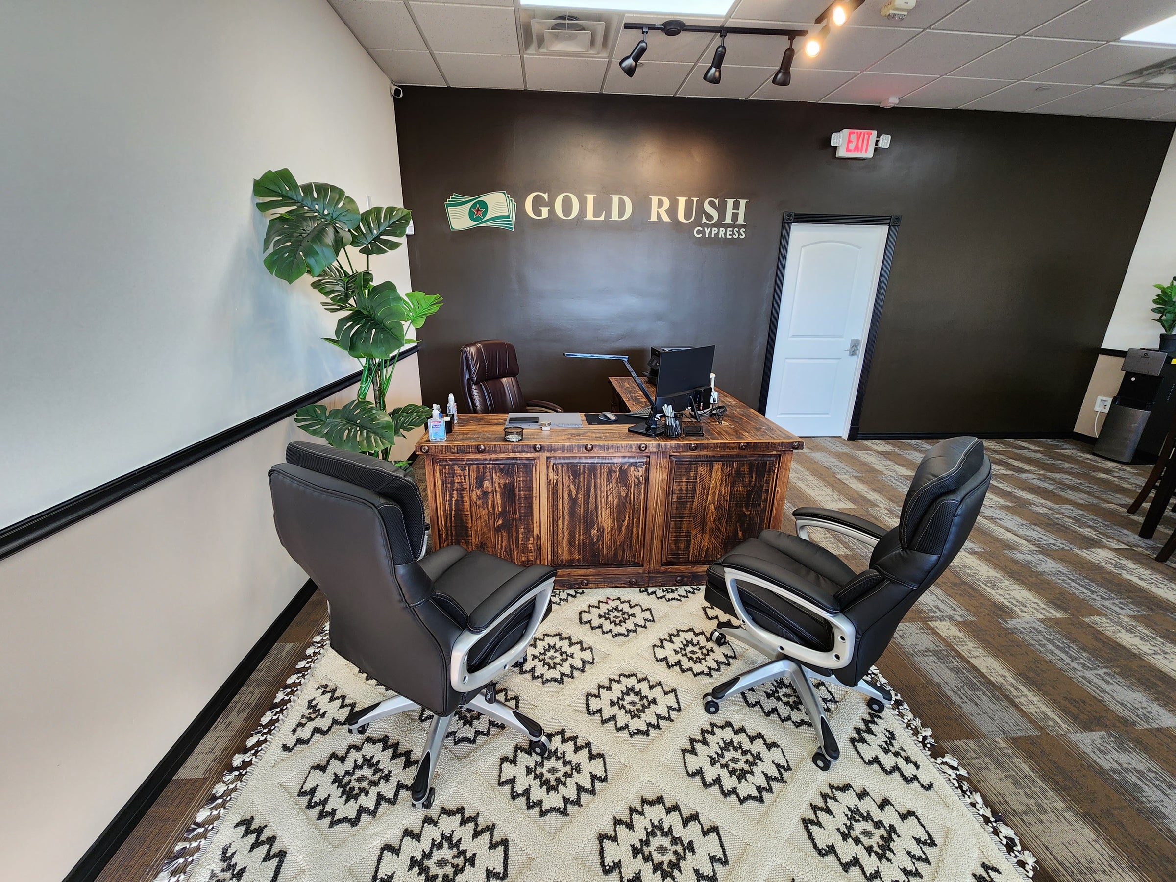Gold Rush Houston office interior with chairs and desk, and the Gold Rush sign on the wall. Represents a relaxed and easy process of selling gold at Gold Rush Houston.
